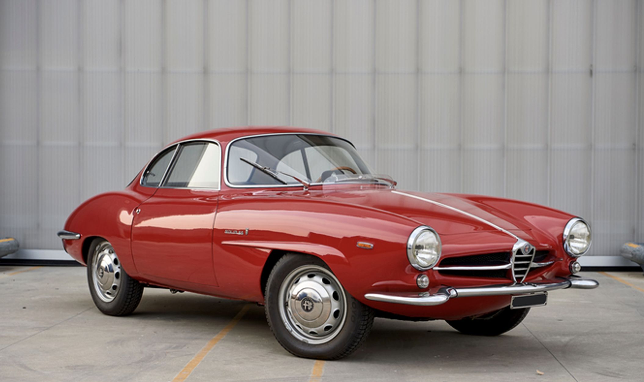 Alfa Romeo rossa sportiva d'epoca con fari rotondi e griglia cromata.