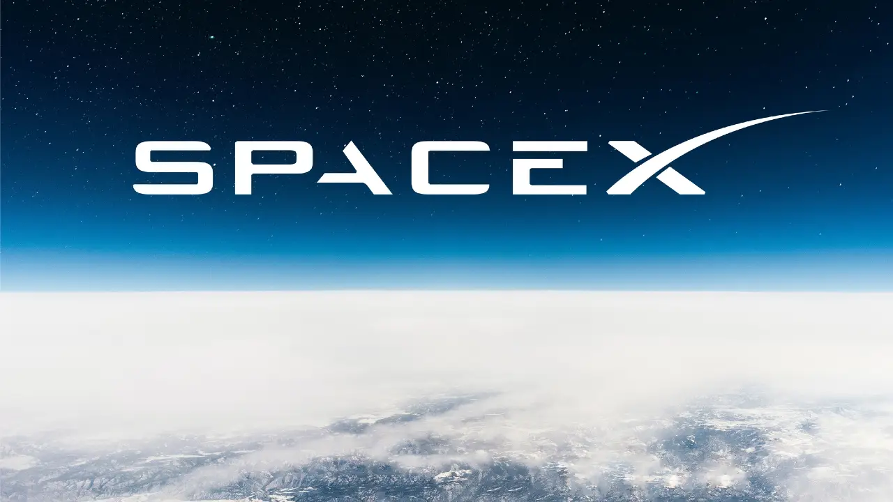Logo SpaceX bianco su sfondo blu stellato, sopra nuvole e terra innevata.