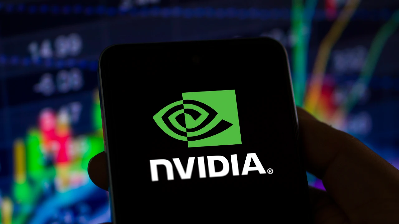 Logo NVIDIA su smartphone, con grafico finanziario sfocato sullo sfondo.