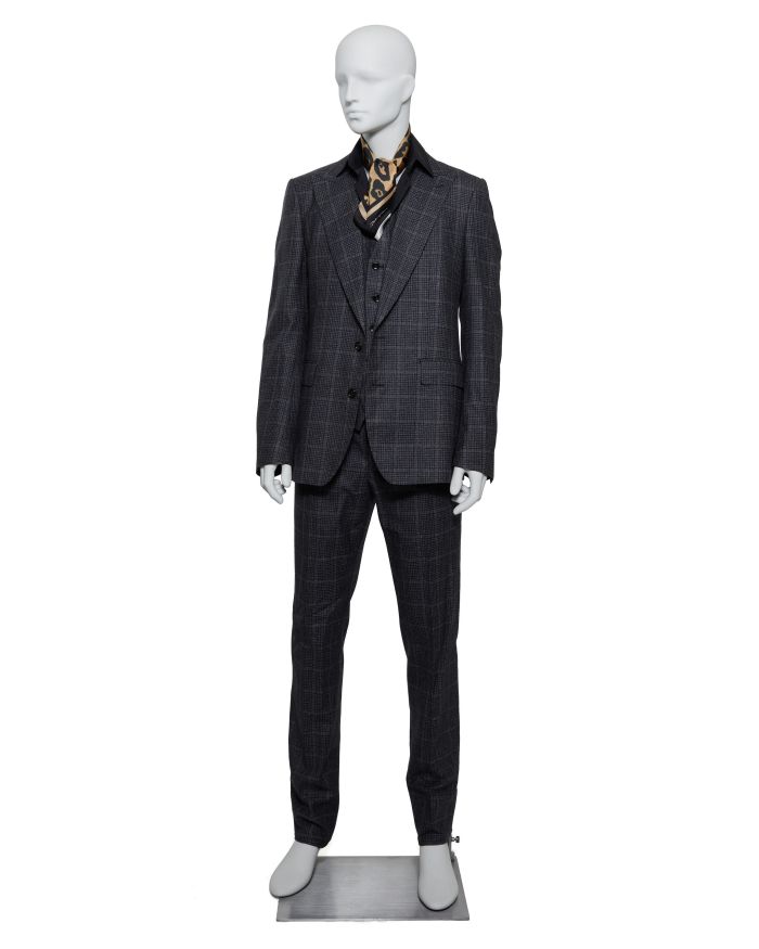 Manichino con abito gessato grigio, gilet, camicia nera e foulard con stampa animalier.
