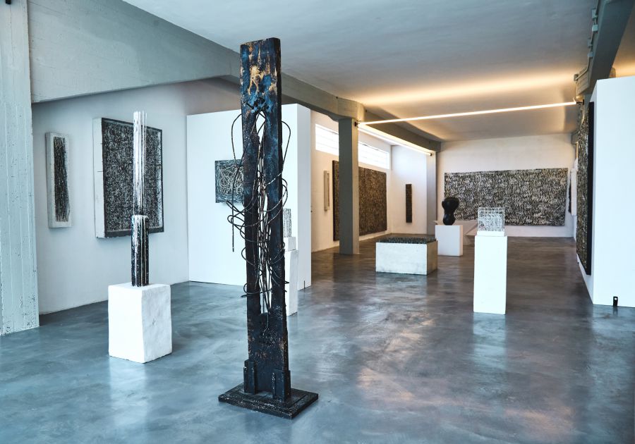 Galleria d'arte con sculture astratte, quadri e installazioni su piedistalli bianchi.