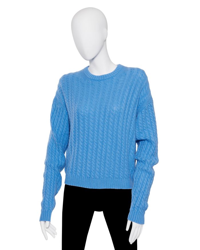Maglione blu a trecce su manichino, con pantaloni neri.