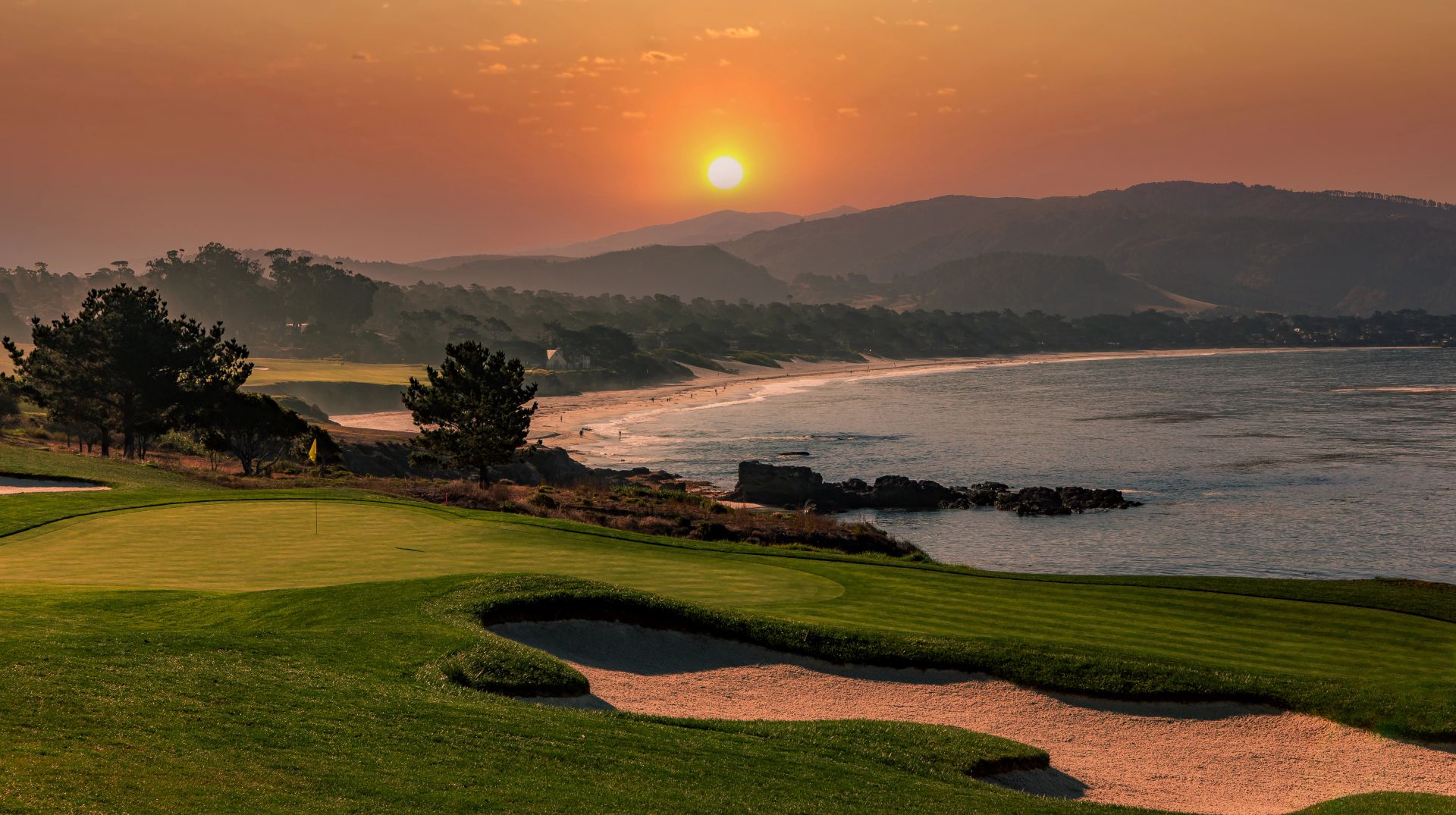 Tramonto sul campo da golf con vista sull'oceano, spiaggia e montagne.