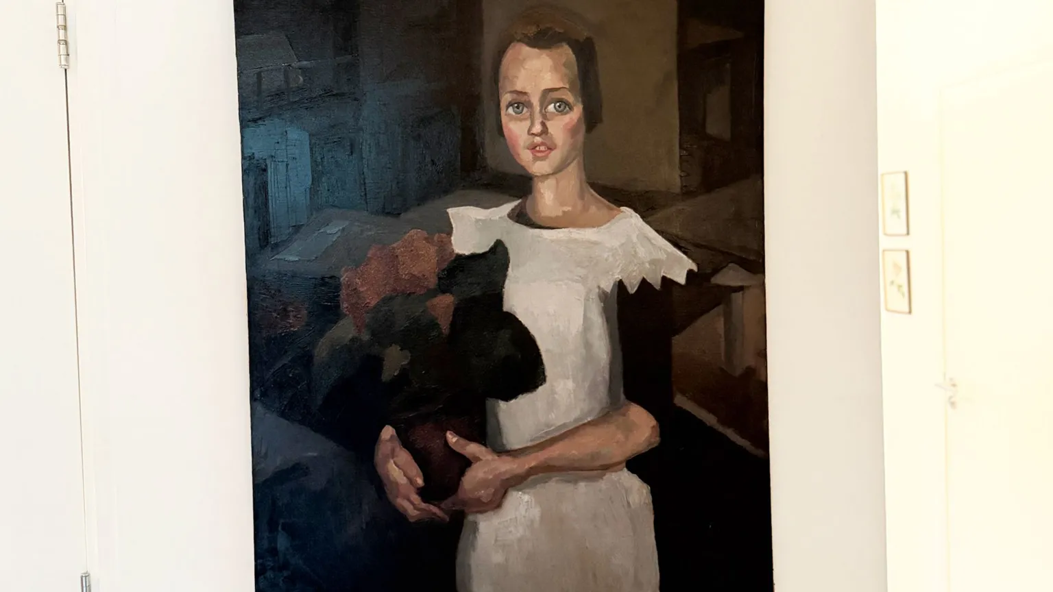 Ritratto di bambina con fiori scuri e gatto nero, indossa un vestito bianco.