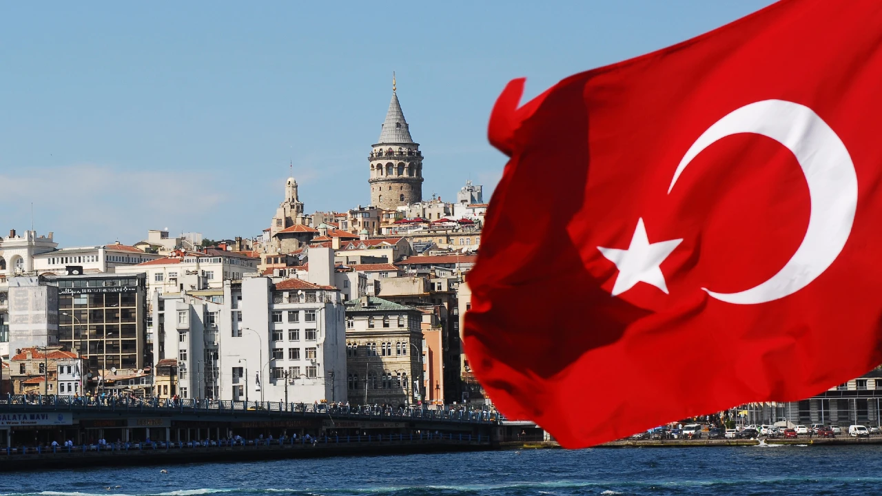 Bandiera turca in primo piano, con la Torre di Galata e lo skyline di Istanbul sullo sfondo.