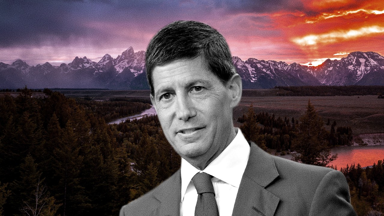 Uomo in abito con montagne innevate e tramonto infuocato sullo sfondo.