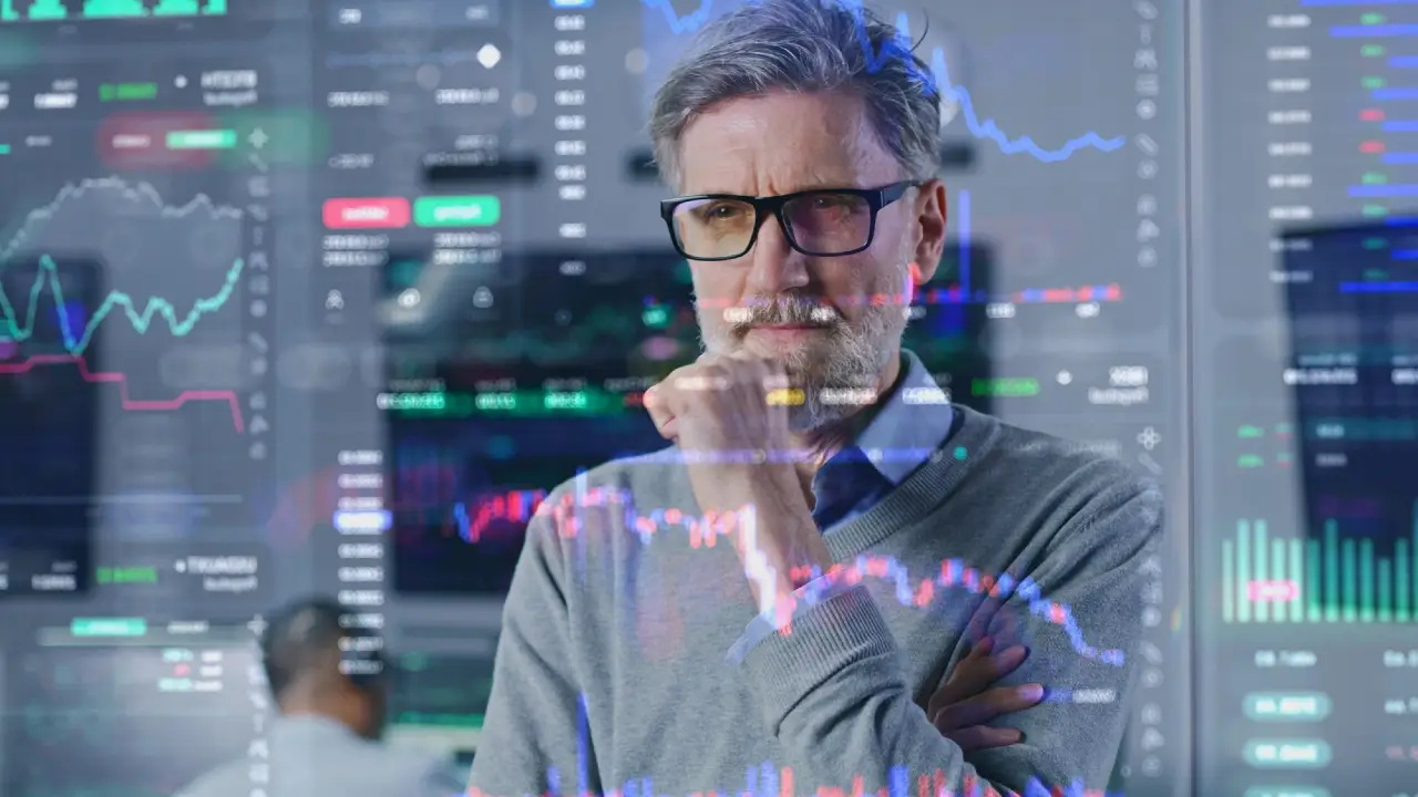 Uomo con occhiali riflette su grafici finanziari sovrapposti.