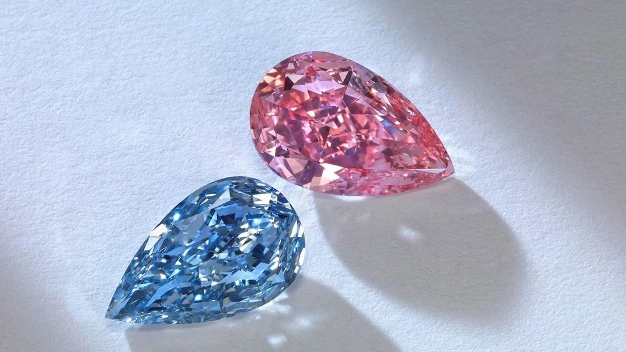 Due diamanti a forma di pera, uno blu e uno rosa, su sfondo bianco.