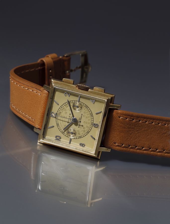 Orologio da polso quadrato in oro con cinturino in pelle marrone, quadrante con cronografo e numeri arabi.