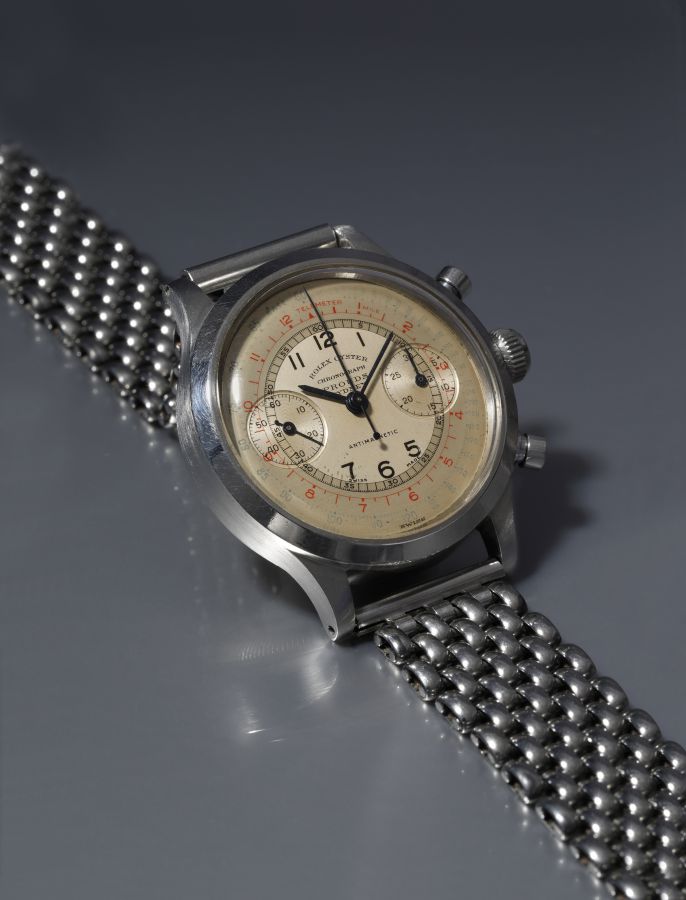 Orologio Rolex Oyster Chronograph con quadrante chiaro, numeri arabi e cinturino in maglia metallica.
