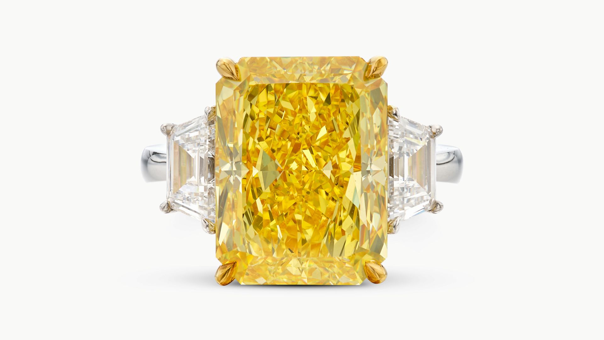Anello con grande diamante giallo rettangolare e due diamanti bianchi laterali.