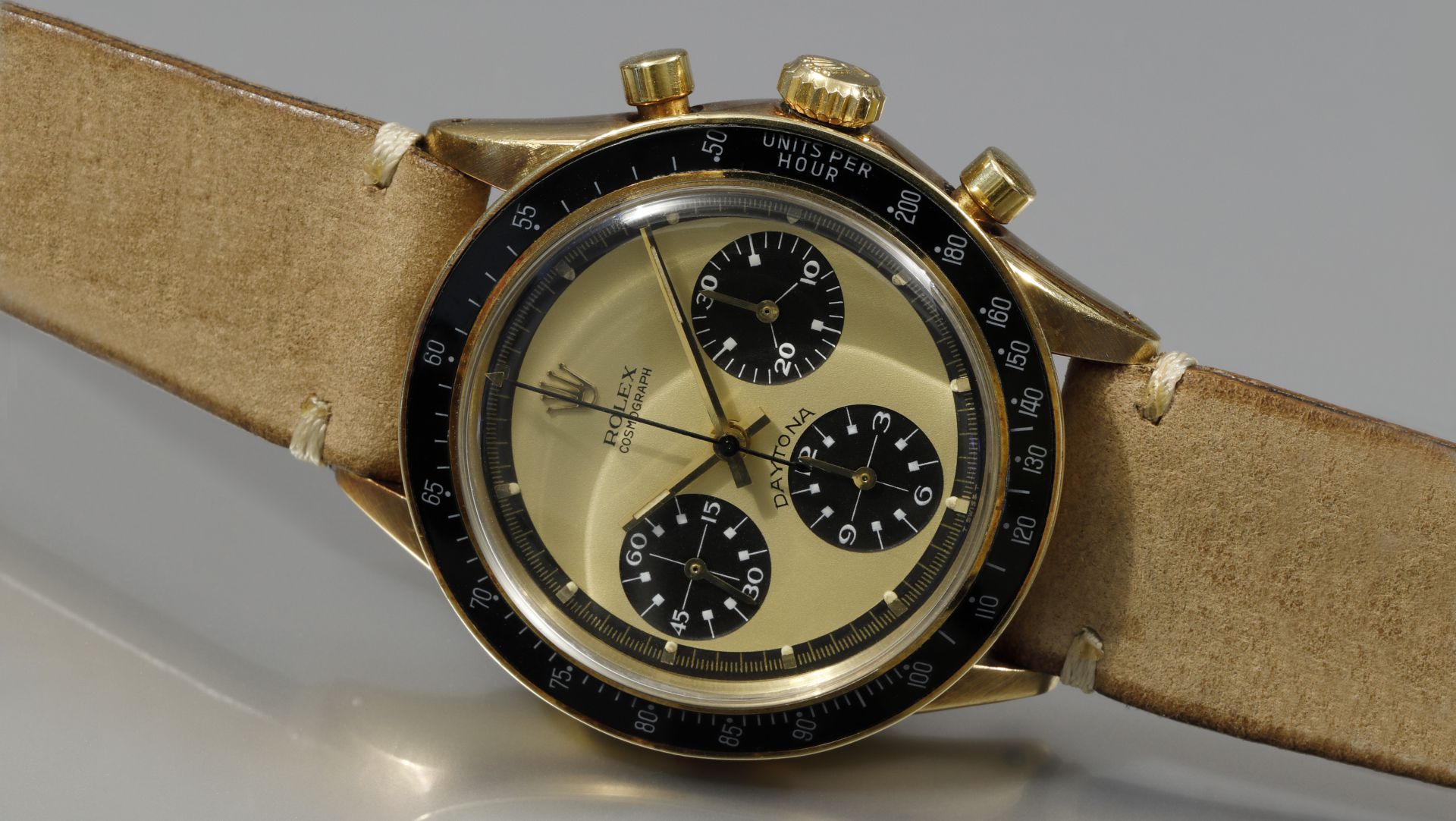 Orologio Rolex Daytona in oro con quadrante champagne, cinturino in pelle scamosciata marrone.