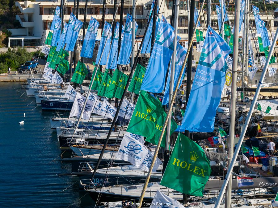 Vele blu e verdi con loghi Rolex e "Swan Cup 2026" su barche ormeggiate.