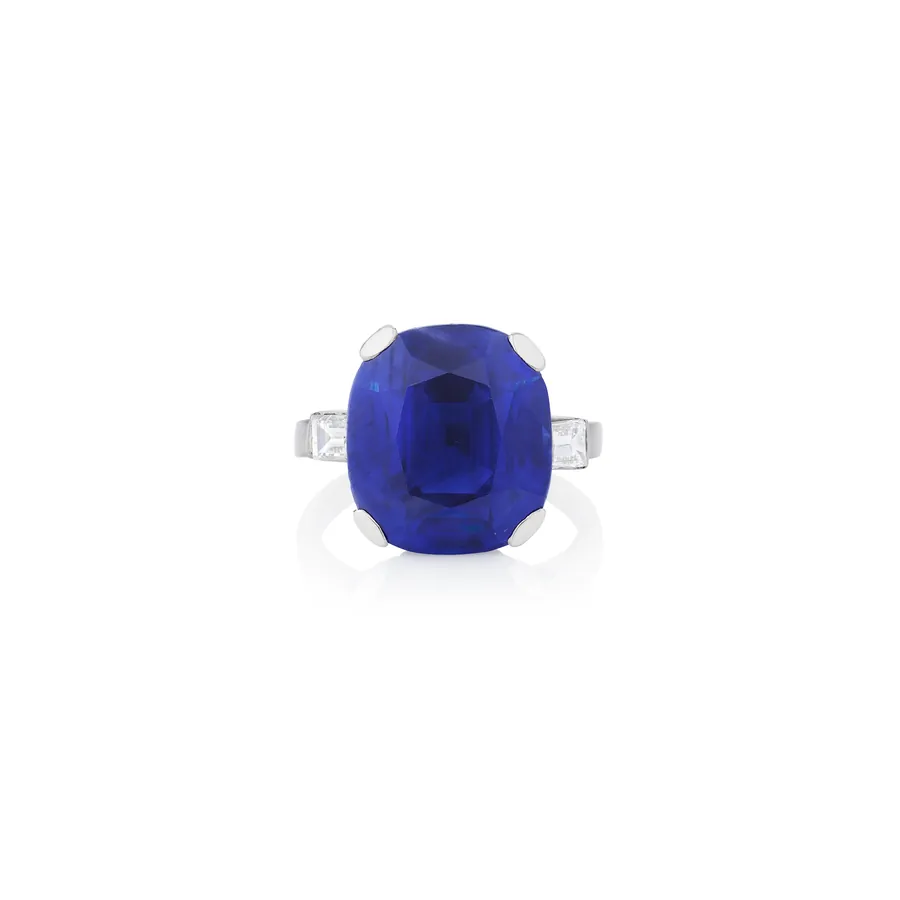 Anello con grande zaffiro blu a cuscino e diamanti rettangolari laterali.