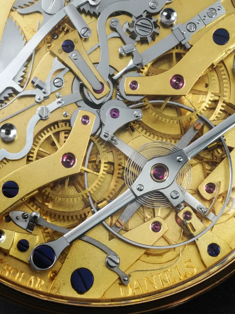 Meccanismo interno dorato di un orologio con ingranaggi, viti e rubini visibili.