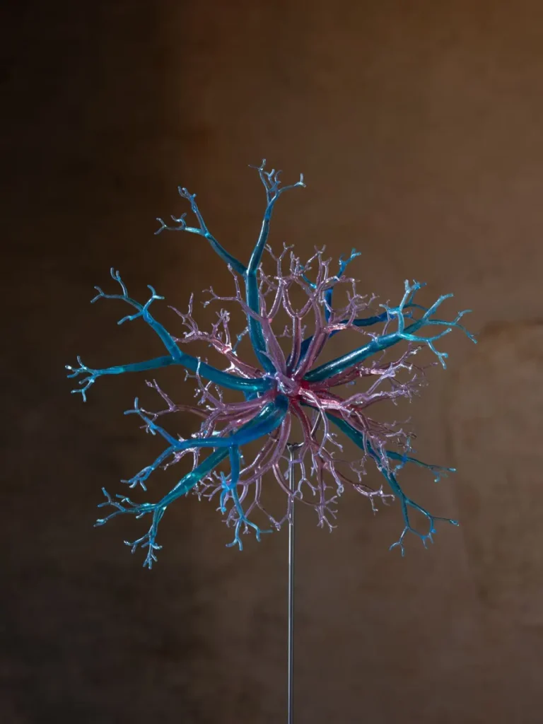 Struttura ramificata blu e rosa su asta metallica, simile a un neurone o un fiore astratto.