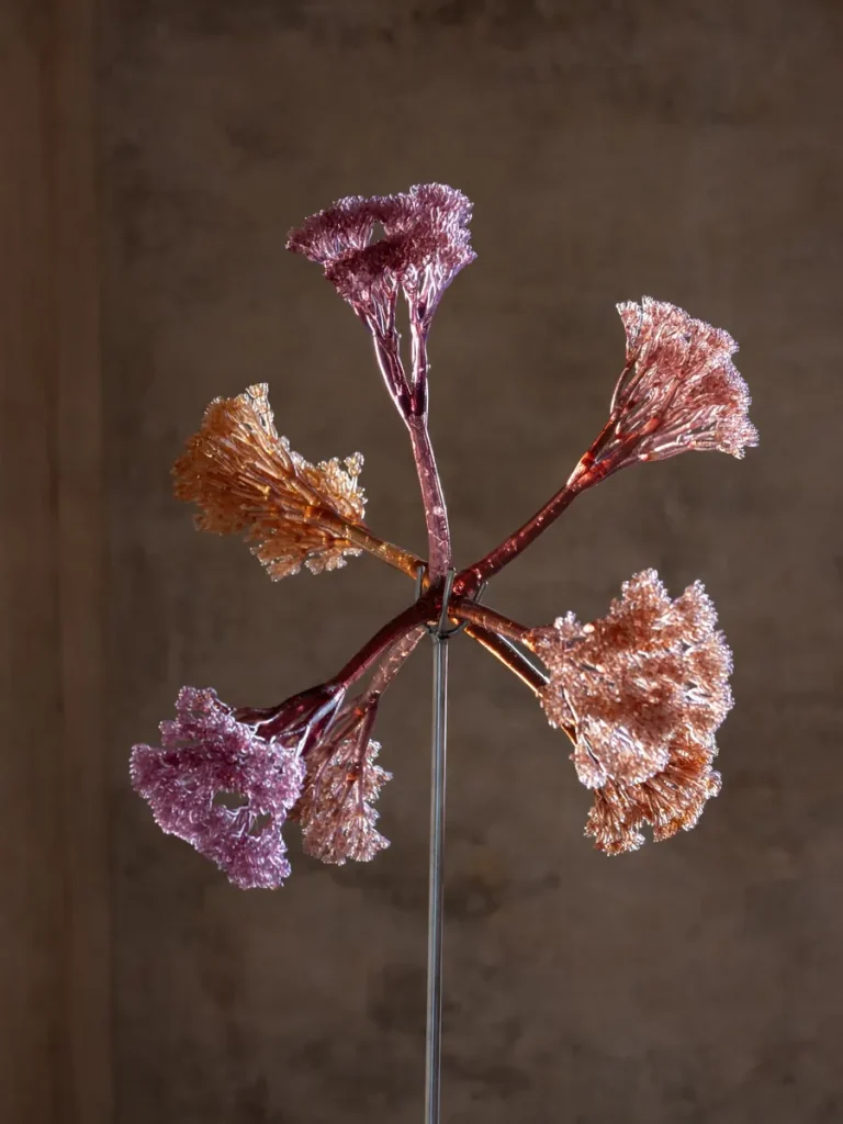 Scultura di vetro colorato a forma di fiore su asta metallica.