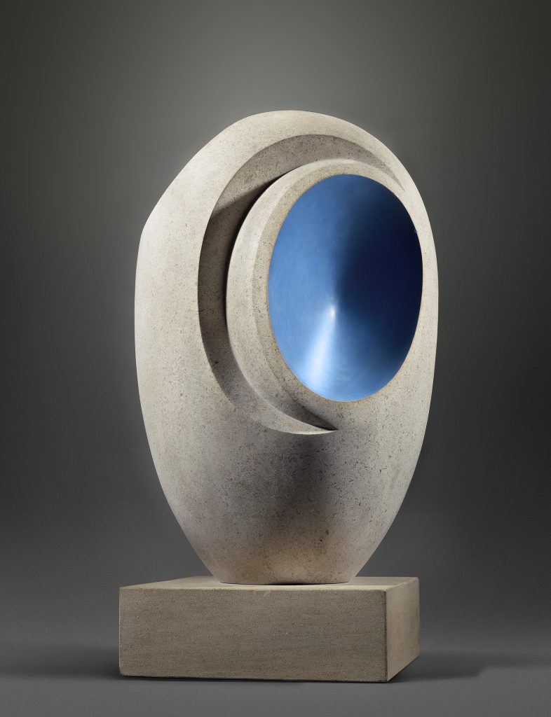 Scultura astratta in pietra chiara con interno blu brillante su base squadrata.