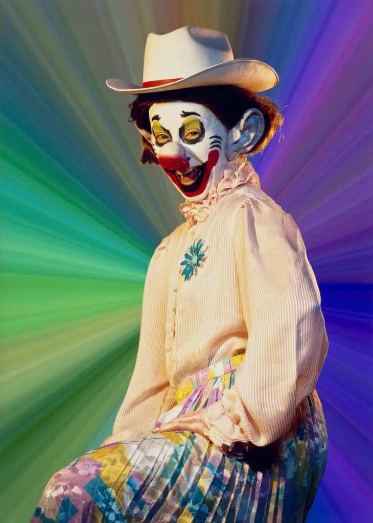Clown con cappello da cowboy, trucco vivace, camicia a balze e gonna a pieghe colorata.