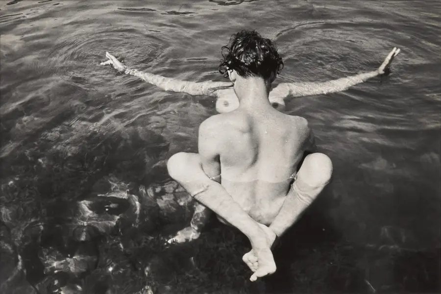Due persone nude nell'acqua, una di schiena, l'altra con le braccia tese.