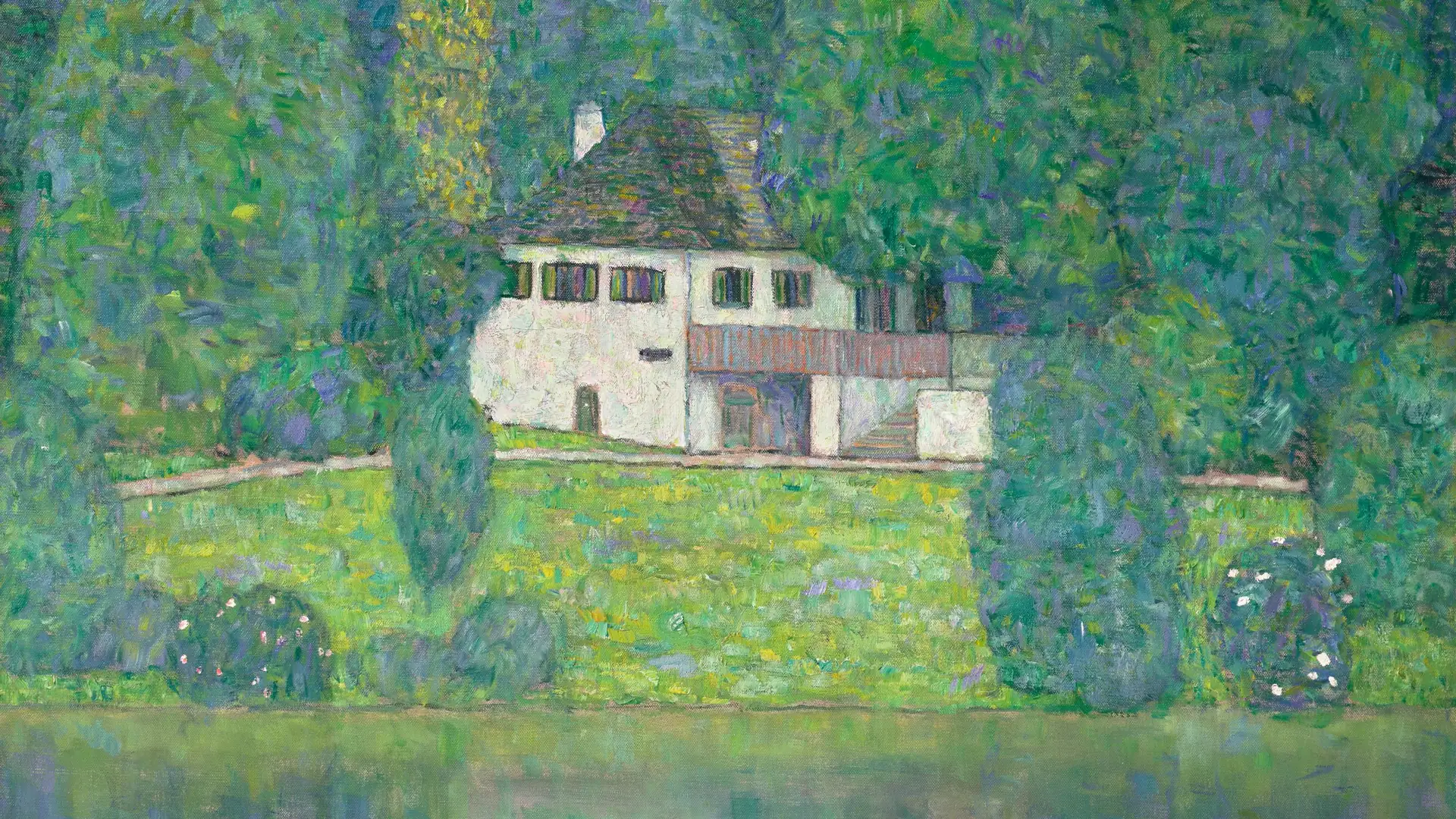 Casa bianca circondata da alberi verdi e rigogliosi, con un prato e un lago.