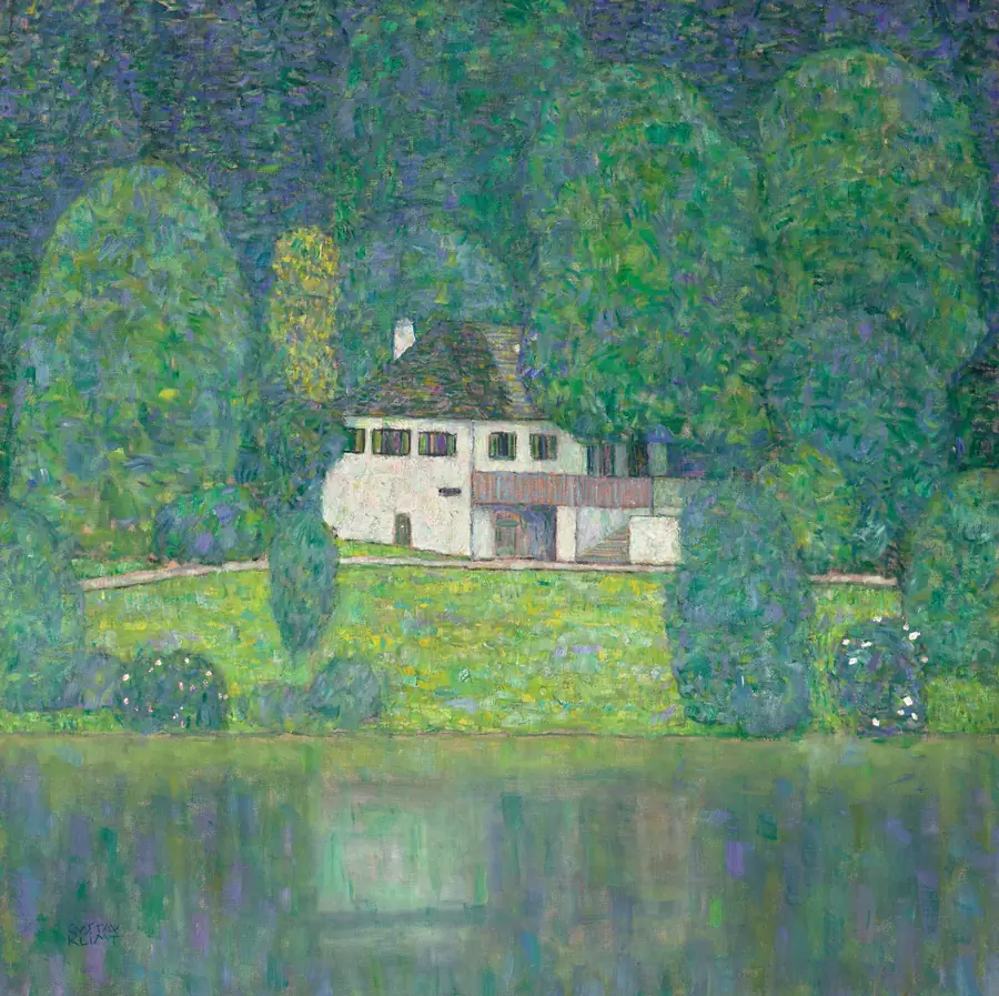 Casa bianca su una collina verde, circondata da alberi, con un lago riflettente in primo piano.