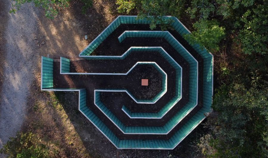 Labirinto ottagonale con pareti di vetro verde e un quadrato arancione al centro.
