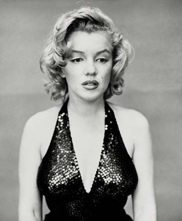Marilyn Monroe con abito scollato e paillettes, capelli mossi, sguardo pensieroso.