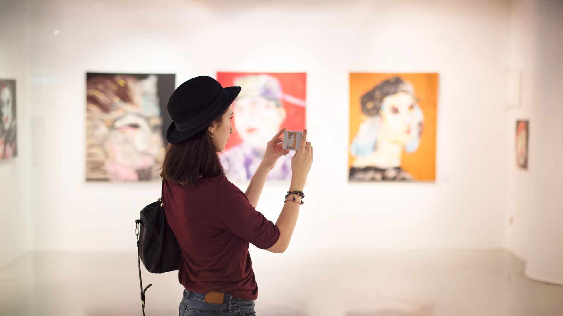 Donna con cappello nero scatta foto a quadri colorati in una galleria d'arte rappresenta i dati del primo Stella Report sulle collezioniste