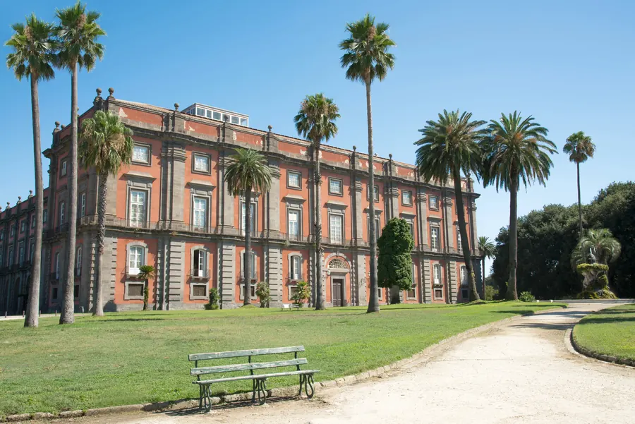 Palazzo reale con palme, prato verde e panchina.