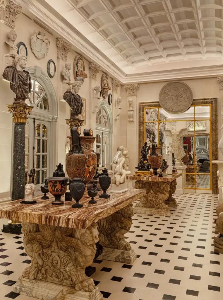 Stanza con sculture classiche, vasi antichi e busti su tavoli di marmo e pavimenti a scacchi.
