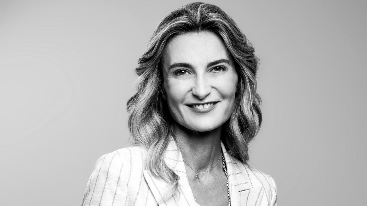 Donna sorridente con capelli mossi e giacca a righe, in bianco e nero.
