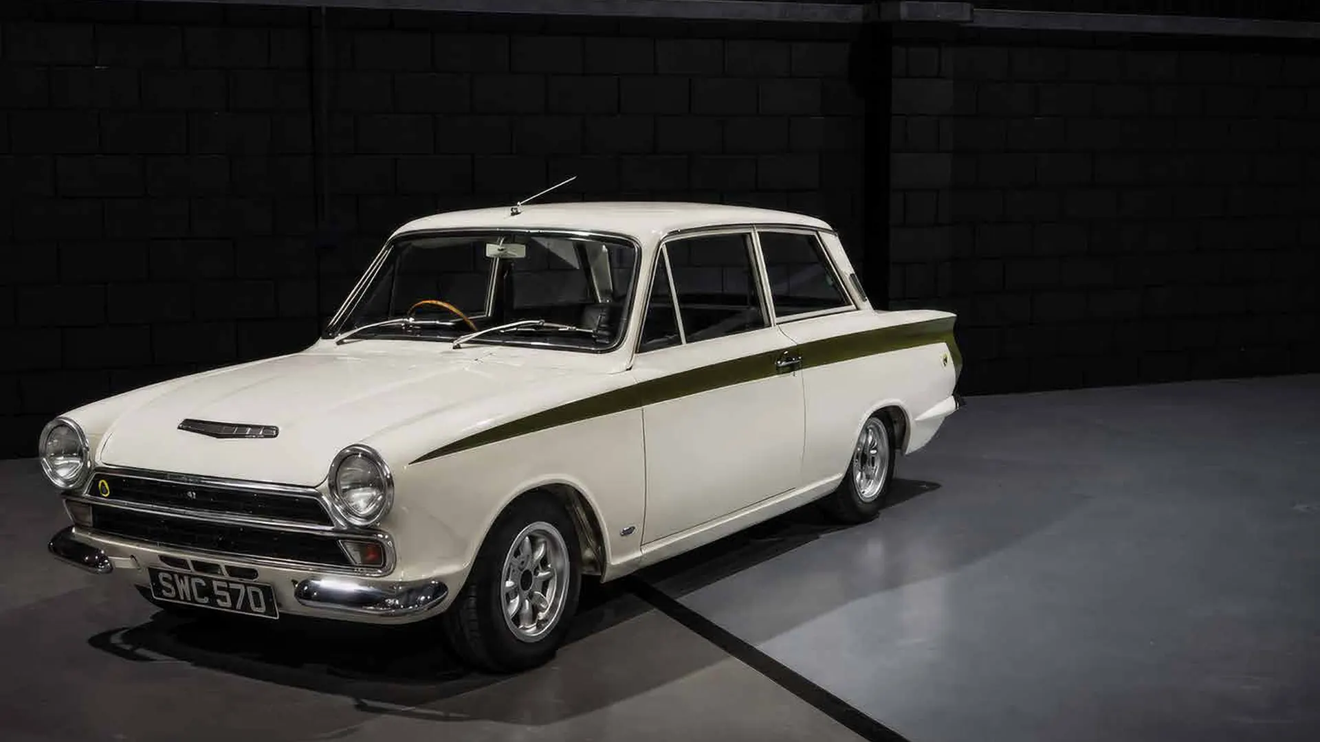 Auto d'epoca bianca con striscia verde, su sfondo scuro.