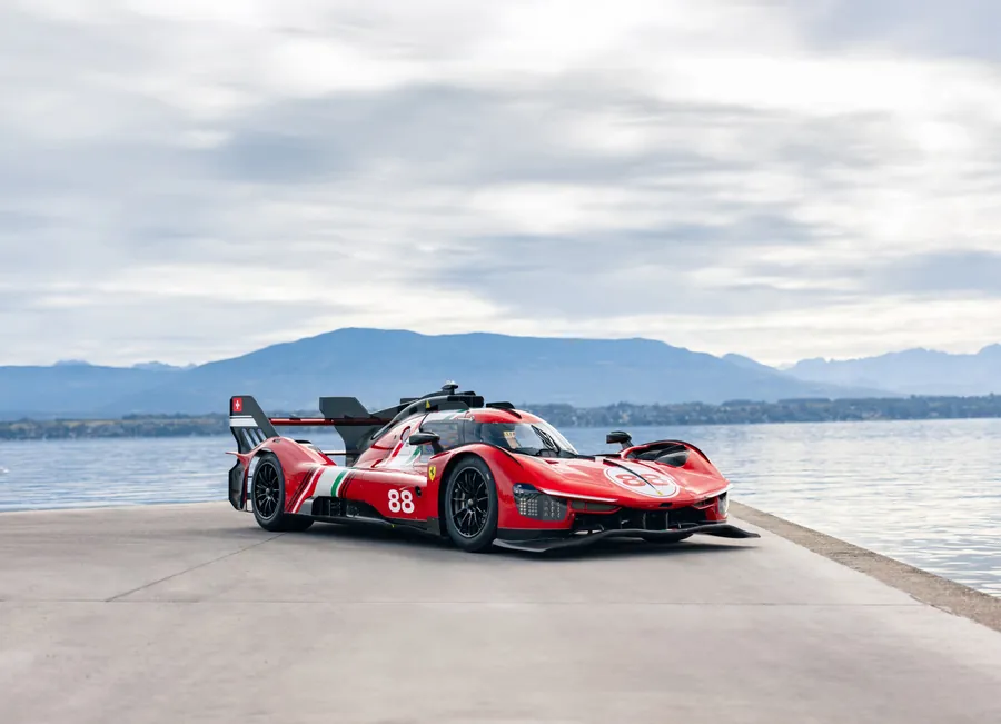Auto da corsa rossa Ferrari con numero 88, parcheggiata sul lungomare con montagne sullo sfondo.