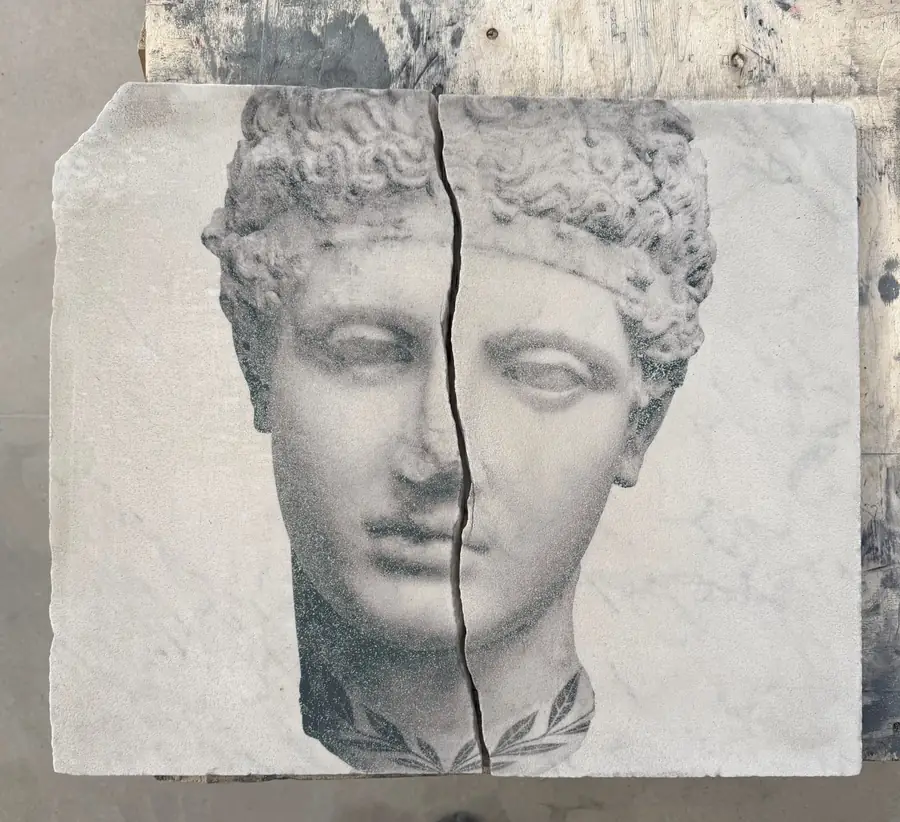 Busto di marmo diviso verticalmente, con volto classico e corona d'alloro.